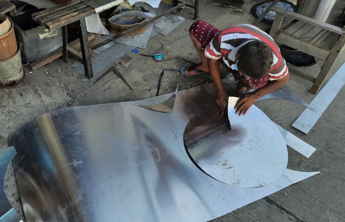 Perajin memotong plat logam menjadi lingkaran, Rabu, 16 Juni 2021. Proses ini membutuhkan pengalaman serta ketelitian. (Serat.id/Muhammad Taufiqurrohman)